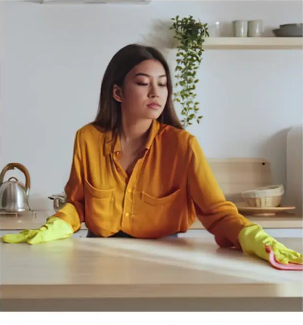 Woman in yellow rubber gloves wiping a kitchen counter with a pink cloth